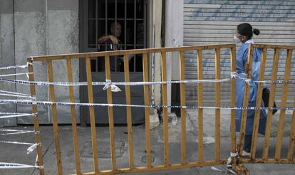 Una funcionaria del Ministerio de Salud conversa el pasado 5 de julio con un hombre que está bajo medidas sanitarias junto a otras 50 personas en un recinto de alquileres de habitaciones intervenido por las autoridades, en San José (Costa Rica), donde el día antes falleció una persona por Covid-19.