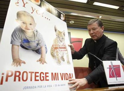 El portavoz de la Conferencia Episcopal, Juan Antonio Martínez Camino, coloca el cartel de la campaña contra el aborto.