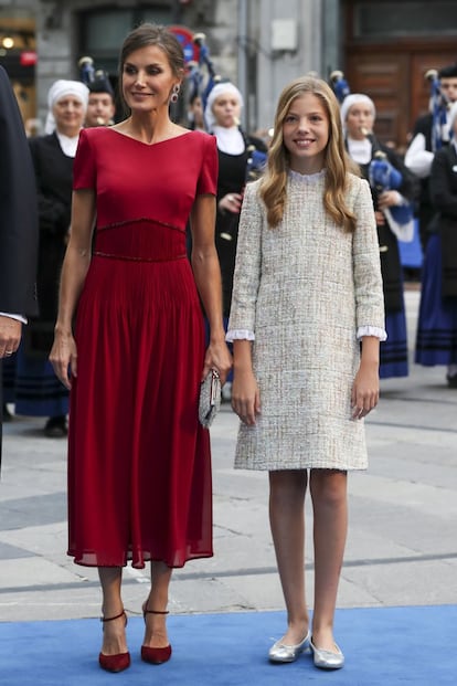 Para la entrega de premios de 2019, la reina Letizia (aquí junto a su hija menor, la infanta Sofía) ha optado por un vestido rojo de manga corta y a media pierna con la cintura plisada, diseñado por Felipe Varela, como es tradición. Además, ha llevado zapatos con pulsera a juego y un bolso en color plata.
