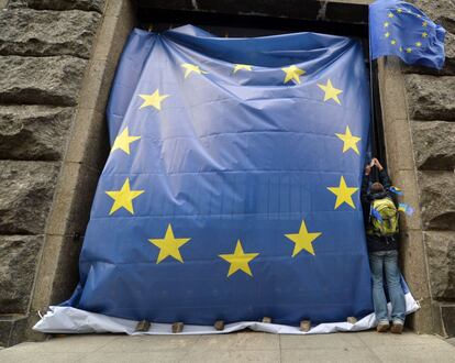 Un hombre coloca una bandera europea gigante en el acceso a la sede del Ejecutivo de Ucrania.