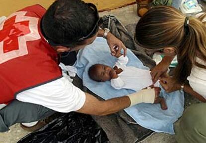 Voluntarios de la Cruz Roja atendieron ayer al bebé interceptado junto a 27 inmigrantes más en Algeciras.