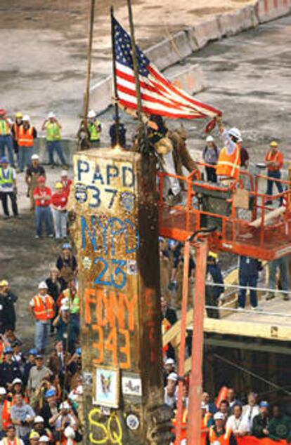 Una bandera de EE UU es colocada sobre un pilar de las Torres Gemelas, en la <i>zona cero</i> de Nueva York, durante la conclusión de los trabajos de desescombro.