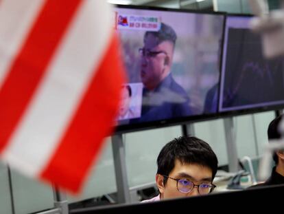 Un operador del mercado de divisas en Tokio (Japón) con una imagen de fondo del dictador norcoreano Kim Jong un en una pantalla.  