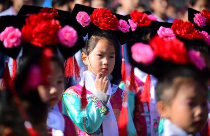Un grupo de estudiantes de primaria vestidos con un traje tradicional chino asiste a un evento deportivo en Shenyang (China).