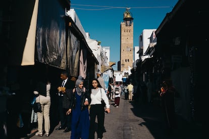 Personas caminan por las calles del casco antiguo de Rabat, repletas de tiendas y con un minarete de mezquita al fondo.