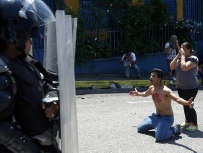 Jovem se ajoelha diante de policiais ap&oacute;s morte de colega.