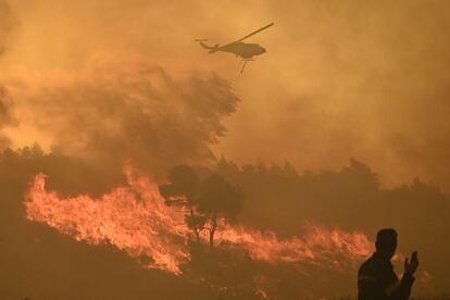 A firefighting helicopter makes a water drop as a wildfire burns in the village of Varnava, near Athens, Greece, August 11, 2024.