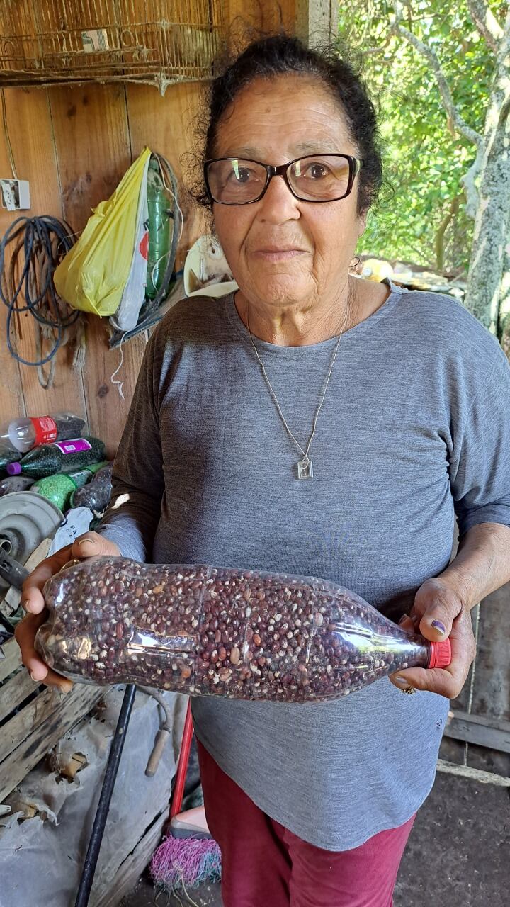 Doña Vera Alves sostiene una botella repleta de semillas.