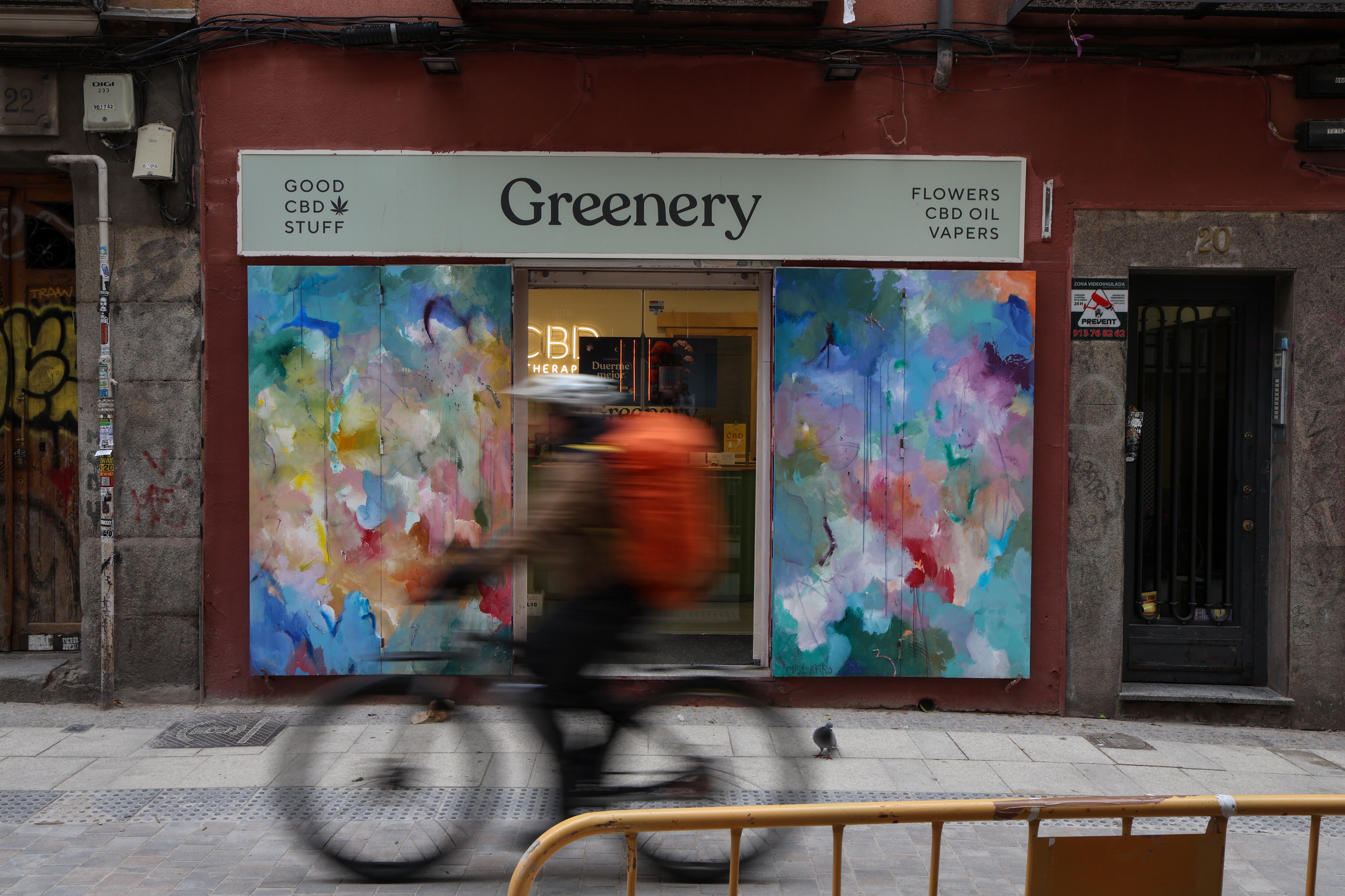 Un 'rider' pasa frente a una tienda de CBD en Malasaña, Madrid, el 30 de enero de 2026. Antes había una frutería que llevaba 60 años en el barrio. 
