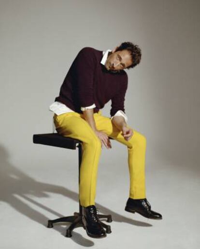 El actor posa con camisa y jersey burdeos Mango Man, pantalón amarillo con raya Bottega Veneta y botines con cordones Mango Man.