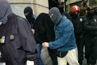 Agentes de la Ertzaintza conducen a uno de los detenidos hasta un garaje de Bilbao registrado ayer.