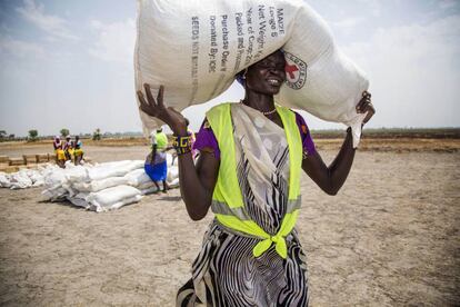 Una voluntaria traslada un saco de semillas en un campo de refugiados en Uganda.