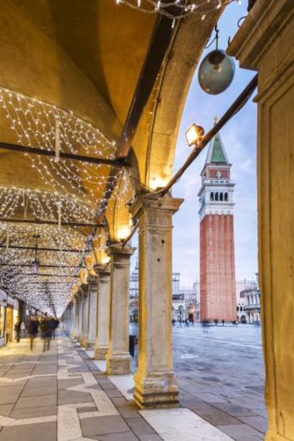 Luces navideñas en los soportales de la plaza de San Marcos, en Venecia (Italia), con la torre del Campanile al fondo.