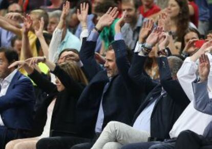 El Rey, en la grada del Palacio, hace la ola durante el partido.