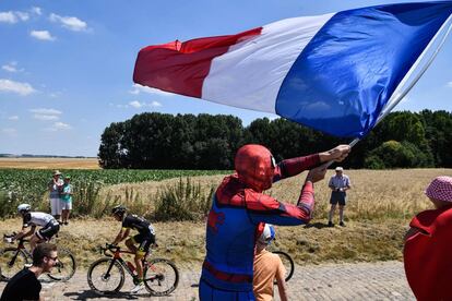 Un aficionado vestido con un disfraz de Spiderman, agita la bandera francesa mientras los ciclistas recorren una sección de adoquines, durante la novena etapa del Tour de Francia, el 15 de julio de 2018.