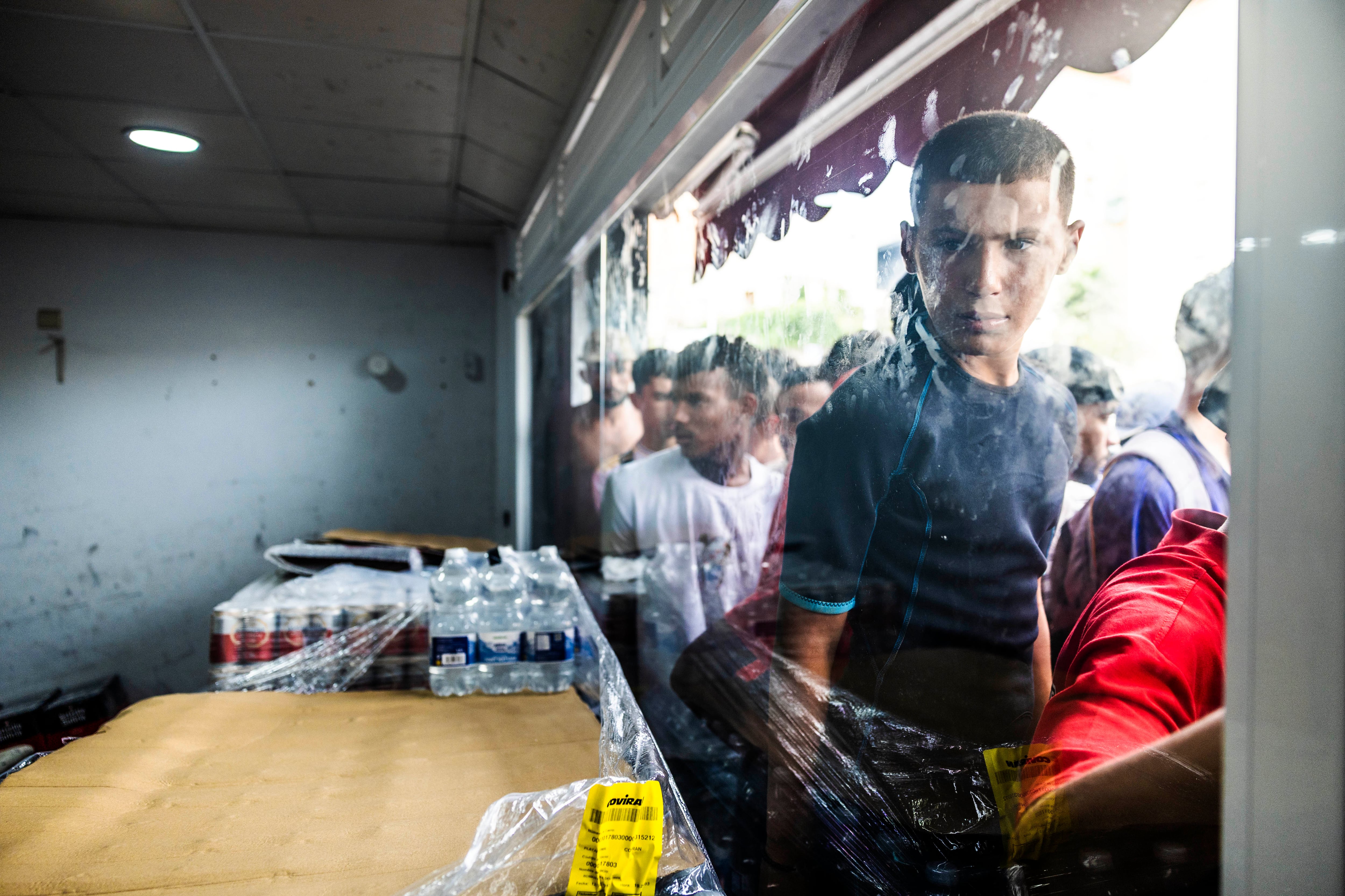 Unos jóvenes hacen cola para comprar víveres en una tienda, este sábado en Ceuta.