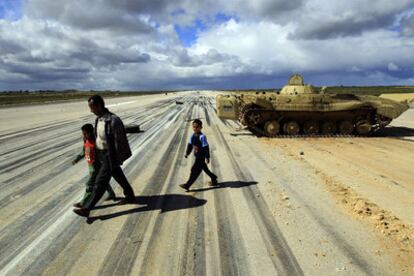 Un hombre atraviesa con sus hijos la pista de un aeropuerto militar en Al Abrak, al este de Libia.