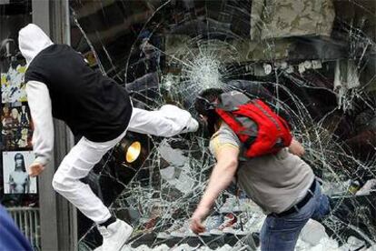 Dos manifestantes destrozan el escaparate de un comercio en el centro de Zúrich (Suiza).
