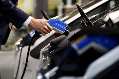 Un hombre recarga un coche eléctrico.