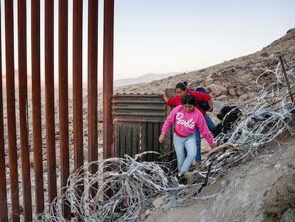 Una madre y su hija cruzan la frontera que separa Estados Unidos de Mexico, Imperial Valley, California, Estados Unidos. La frontera entre EE UU y México abarca cerca de 3.200 kilómetros, lo que la convierte en una de las fronteras más largas del mundo. El proyecto del muro fronterizo se cita a menudo como uno de los esfuerzos de ingeniería más costosos de la historia reciente. Algunas secciones del muro han costado hasta 46 millones de dólares por kilómetro y medio, aunque el promedio ronda entre 20 y 25 millones de dólares, dependiendo del terreno y los desafíos de construcción.