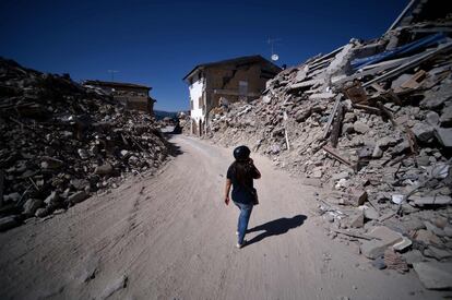 El Gobierno italiano ha instalado 36 casas de acero y madera para que puedan vivir algunos de los evacuados, unos hogares equipados con electrodomésticos y mobiliario, con porche exterior y un pequeño jardín. En la imagen, una mujer camina entre los escombros por el centro de Amatrice.