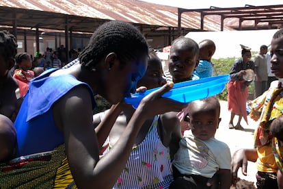 Una mujer bebe agua de la tapa de un cubo en el campamento de Bangula, en Malaui. 