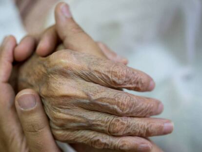 Una persona da la mano a un anciano. 