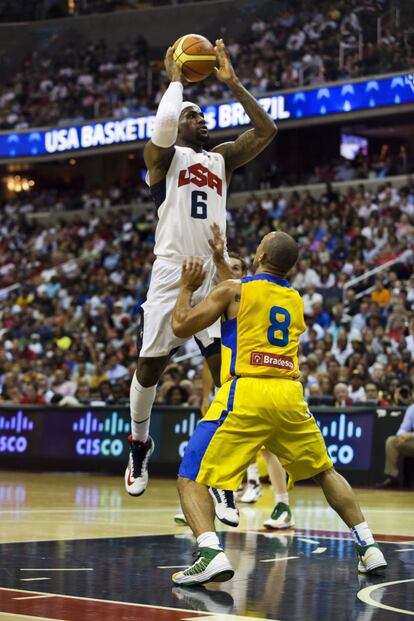 El estadounidense LeBron James salta ante la marca de Alex Ribeiro Garcia de Brasil durante el amistoso jugado entre ambas selecciones en Washington.