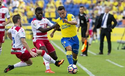 Roque Mesa supera a dos futbolistas del Granada durante el partido del pasado domingo.