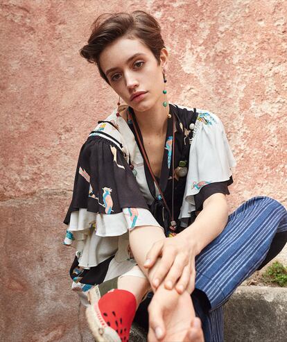 Vestido de volantes (1.200 €), alpargatas (350 €), monedero con forma de kiwi (320 €) y pendientes (220 €), todo de PAULA’S IBIZA LOEWE; y pantalón de lino de TORY BURCH (330 €).