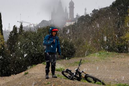 Un ciclista descansa mientras nieva en Collserola. Al fondo , el Tibidabo.