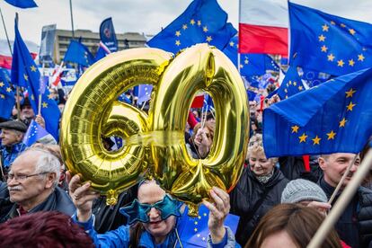 Una mujer sostiene unos globos de aire con los números sesenta para celebrar el aniversario del Tratado de Roma durante una manifestación en Varsovia (Polonia).