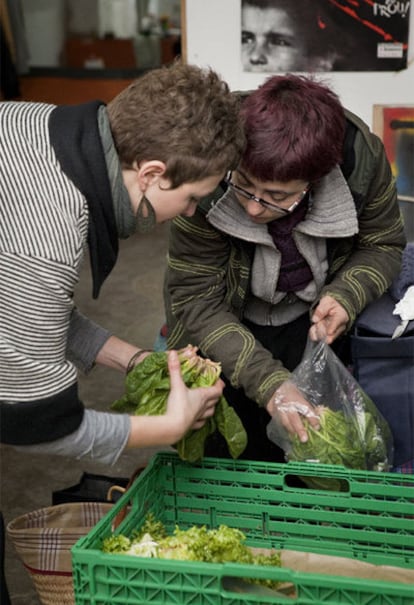 Dos mujeres cogen verdura en una cooperativa del barrio del Clot.