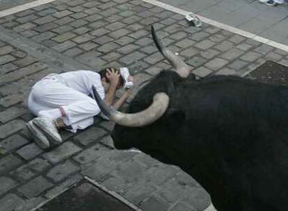 Un mozo caído ante un toro de Antonio Bañuelos a su paso por la curva de Mercaderes.