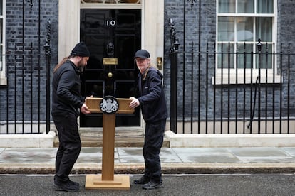 Dos trabajadores colocan un atril en la puerta del número 10 de Downing Street, este viernes. 