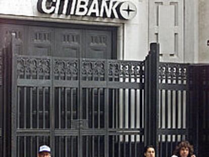 Ciudadanos argentinos descansan en la puerta de un banco en Buenos Aires.