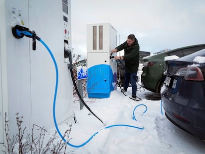 A driver charges an electric car at a parking lot of a shopping mall in Tallinn, Estonia, Saturday, February 11, 2023.