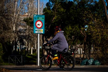 Una persona pasa en bicicleta frente a un cartel que anuncia la zona de bajas emisiones en Madrid.