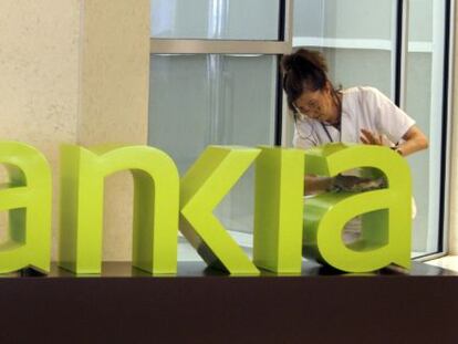 Una operaria limpia el logo de Bankia.