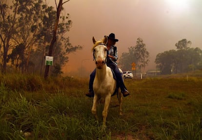 La australiana Rhonda Anderson evacúa sus tierras junto a su caballo durante un incendio cerca de Monte Larcom, en Queensland (Australia). Australia se está viendo afectada por unas condiciones meteorológicas sin precedentes que han causado inundaciones en varios suburbios de Sídney, en el este del país, y decenas de incendios en el estado de Queenland, en el noreste. 