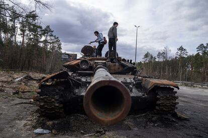 Algunos ucranios se suben a un tanque ruso dañado tras los ataques en Kiev