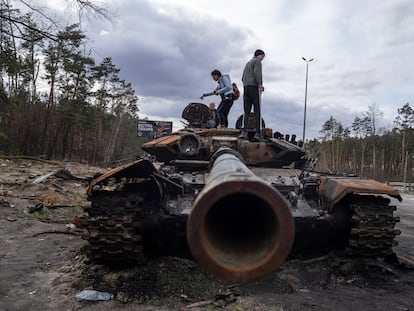 Algunos ucranios se suben a un tanque ruso dañado tras los ataques en Kiev, el 11 de abril.