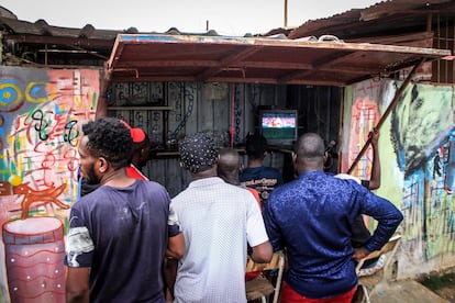 Varios hombres siguen el partido entre Marruecos y Portugal en Luanda (Angola).