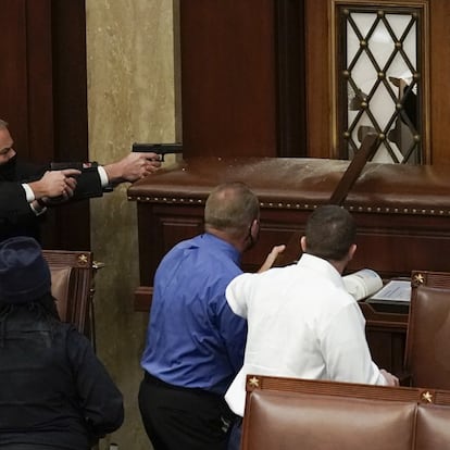 
La policía del Capitolio de los Estados Unidos con armas en la mano observa cómo los manifestantes intentan ingresar a la sesión en la sala principal del Capitolio 