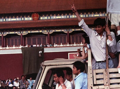 Um manifestante faz o sinal da vitória quando os trabalhadores cobrem um enorme retrato do presidente Mao no Portão da Paz Celestial da Praça Tiananmen, em 23 de maio de 1989.