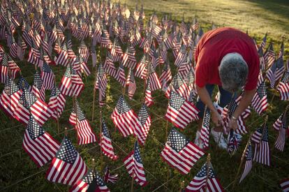 Una mujer coloca banderas estadounidenses en recuerdo a las víctimas de los atentados del 11-S, en un parque de Charlotte, Carolina del Norte, EE.UU.