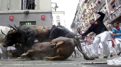 An El Tajo y La Reina ranch fighting bull falls to the ground as it takes the Mercaderes curve during the second running of the bulls of the San Fermin festival in Pamplona, northern Spain, July 8, 2015. One runner was gored in the run that lasted 2 minutes and 14 seconds, according to local media. REUTERS/Susana Vera      TPX IMAGES OF THE DAY     