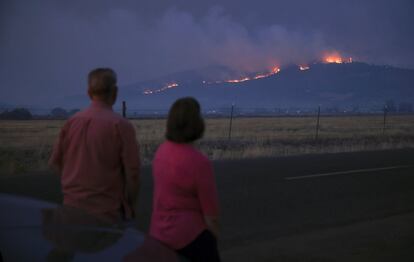 Los residentes miran el humo y el fuego sobre una colina durante los incendios forestales cerca de la ciudad de Medford, Oregón.