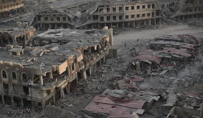 Varias personas caminan entre la ruinas de un barrio de Mosul. 