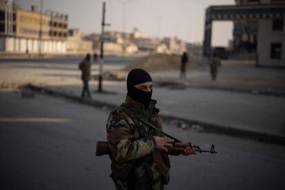 Un miembro de las fuerzas de seguridad vigila  un puesto de control en la ciudad siria de Homs, este jueves.